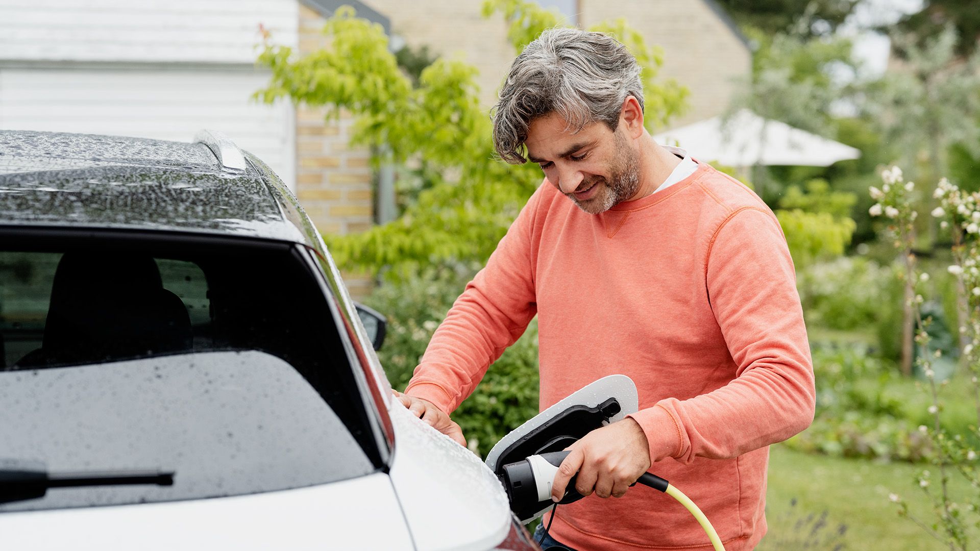 Mand med ladekabel skal lade sin elbil, hvor ladekablet og bilen er omfattet af elbilforsikringen. 