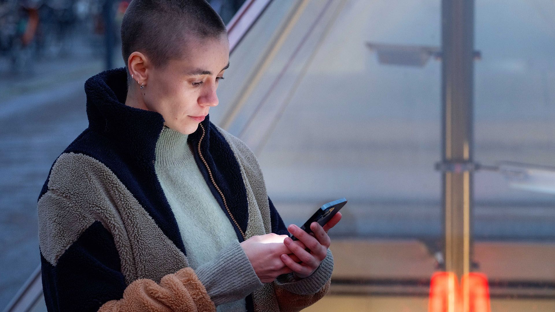 ung studerende kvinde kigger på sin telefon foran metrostation
